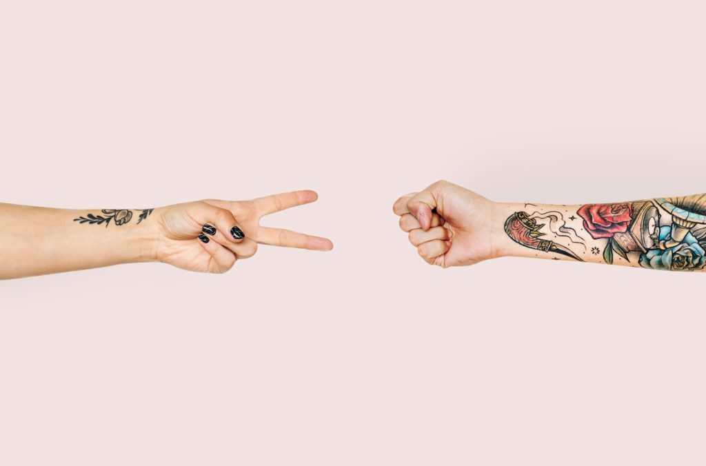 two arms with colorful tattoos