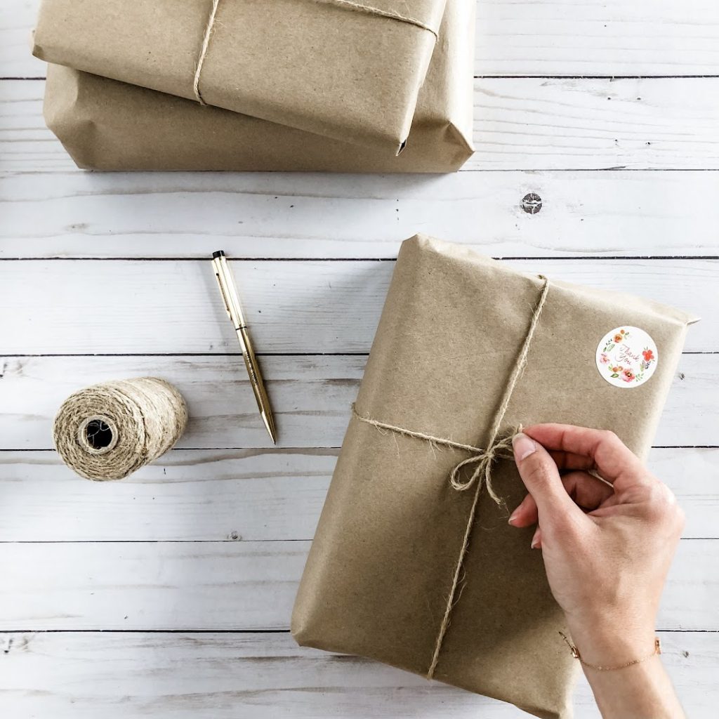 Books wrapped in brown paper and tied with twine on a white wooden background